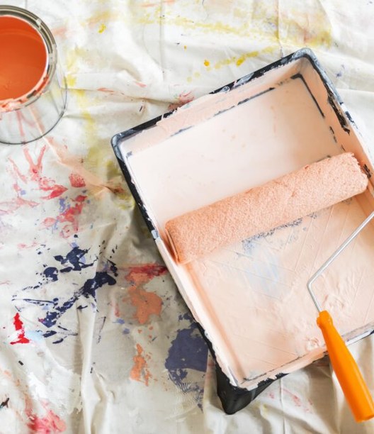 Paint cans and a roller tray on a drop cloth