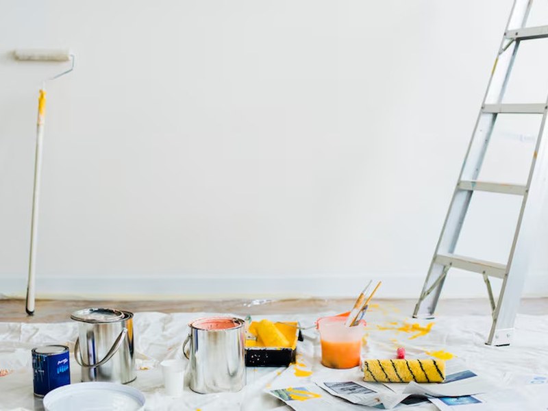 Paint cans, a roller and a ladder ready for a painting job